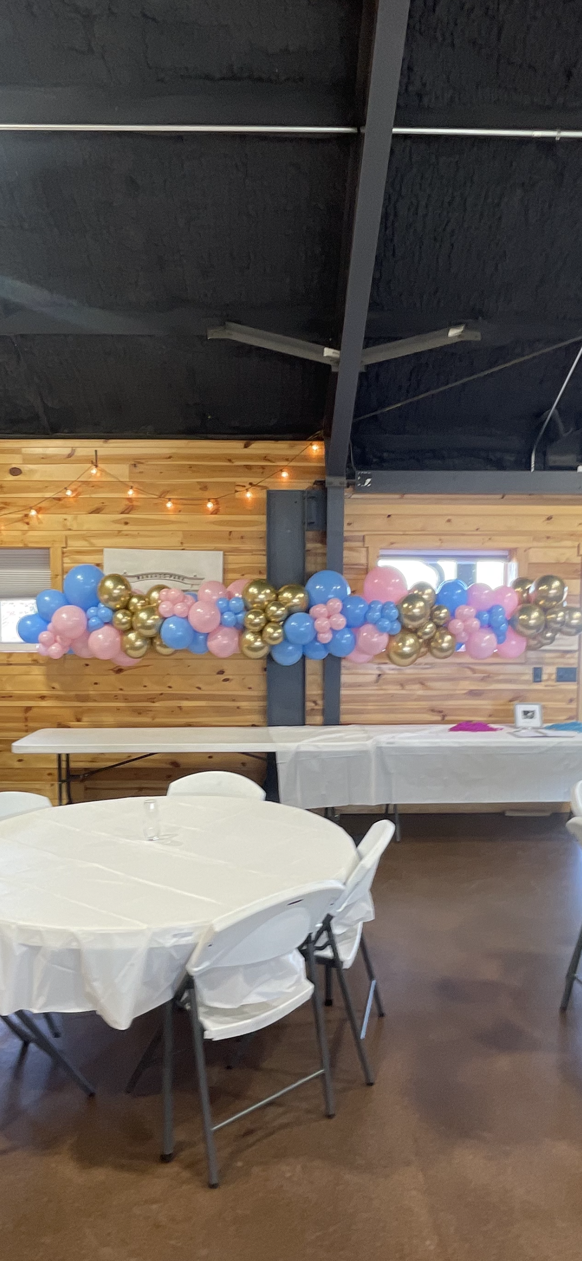 A room with tables and chairs and balloons hanging from the ceiling.
