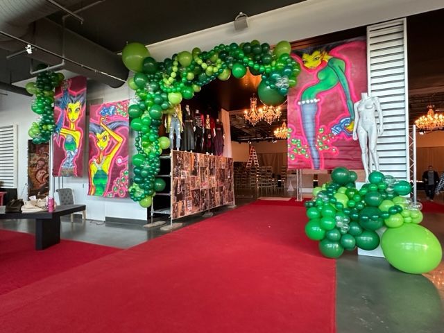 A room decorated with green balloons and a red carpet.