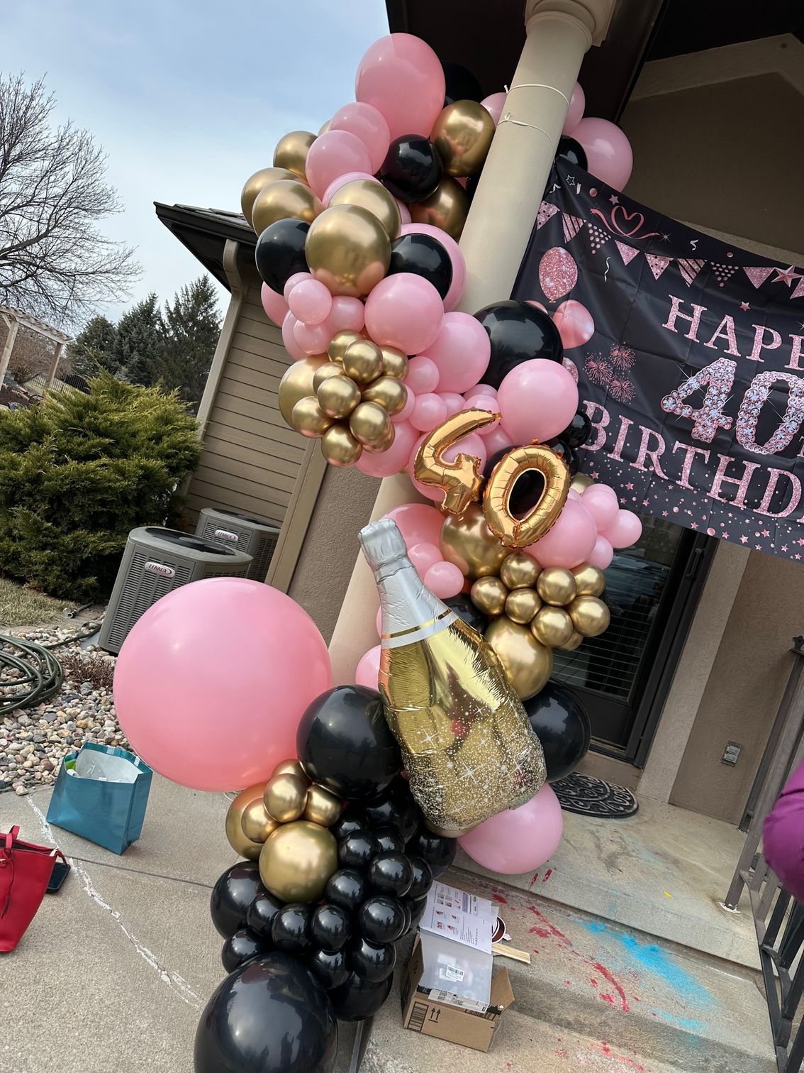 A bunch of balloons are hanging from a pole in front of a house.