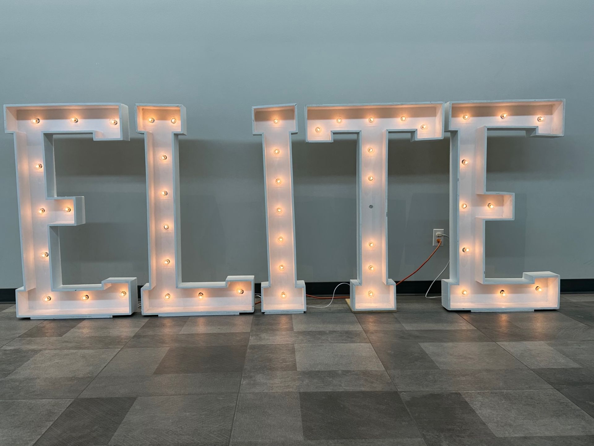 The word elite is lit up on a tiled floor