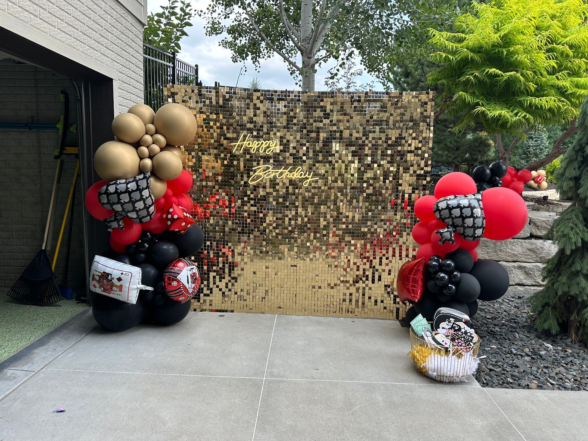 A bunch of balloons are sitting on the sidewalk in front of a wall.