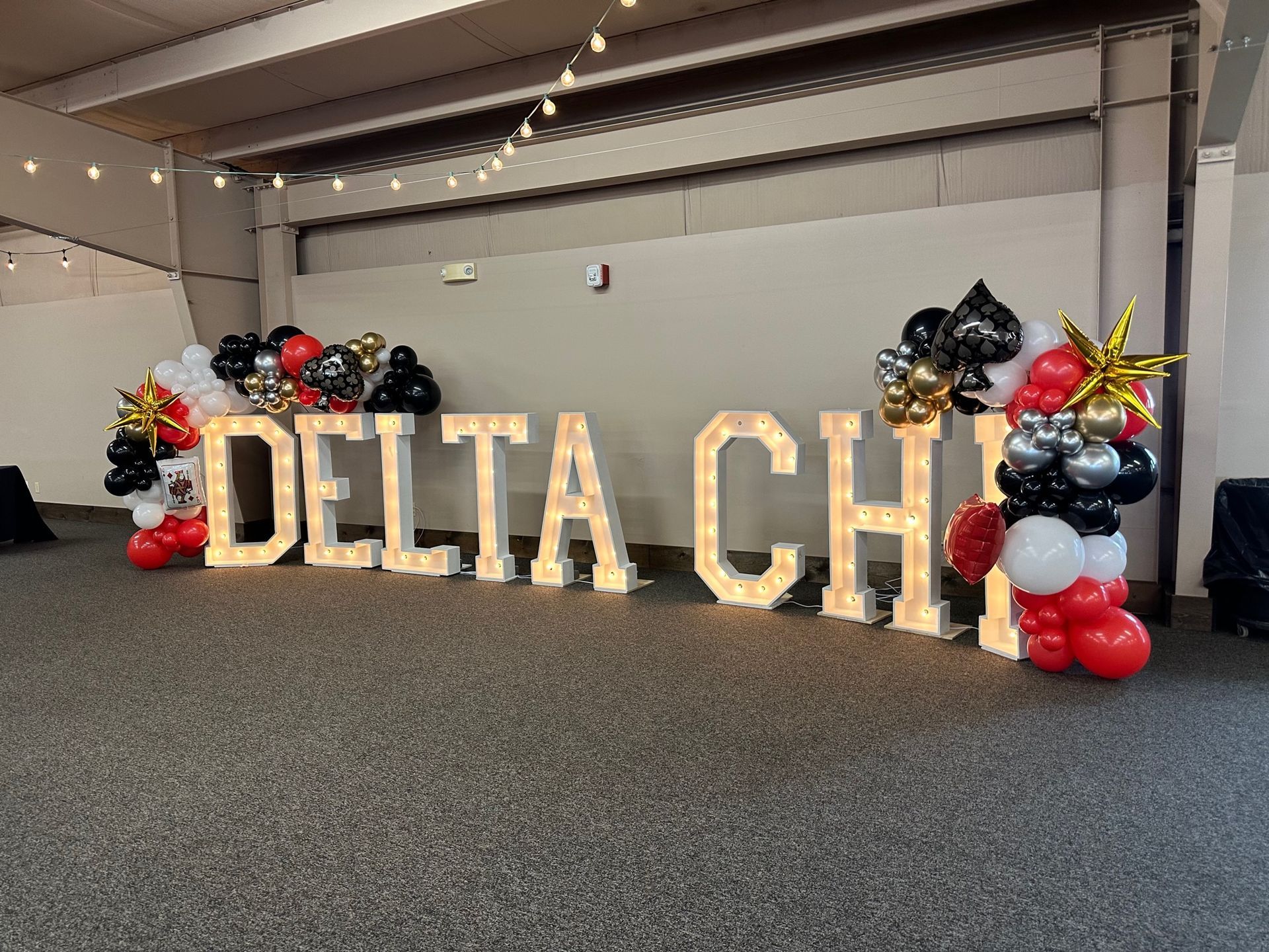 The word delta is surrounded by balloons and lights in a room.