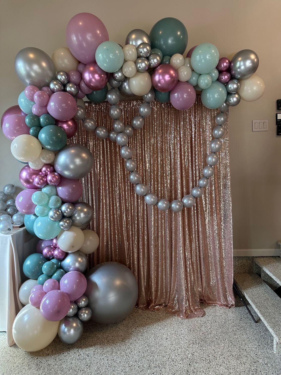 A room filled with balloons and a sequined curtain.