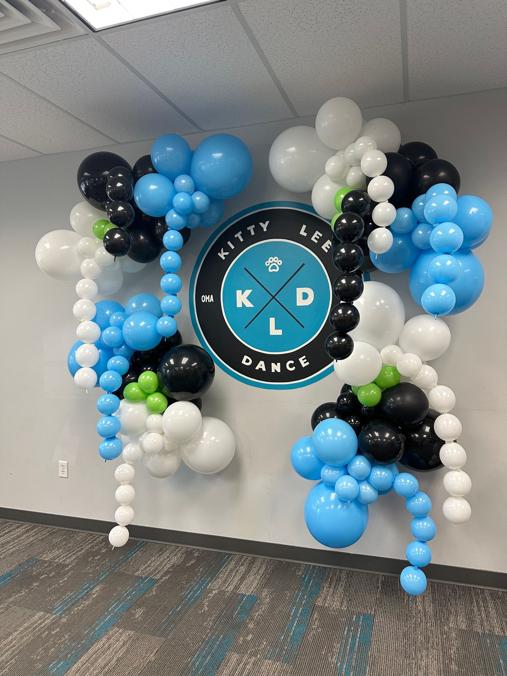 A wall decorated with balloons and a logo for a dance studio