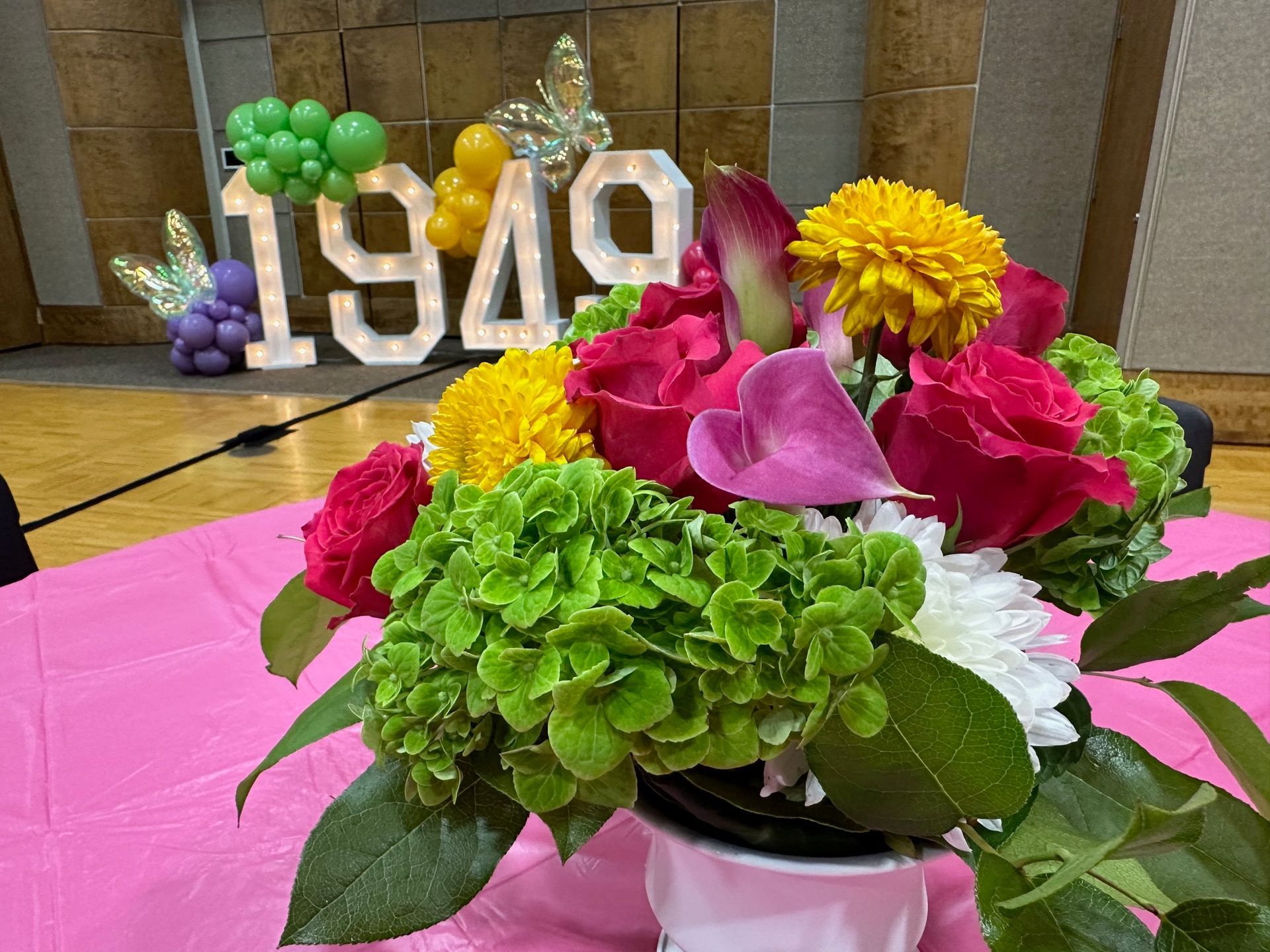 A vase of flowers is sitting on a table in front of a sign that says 1949.