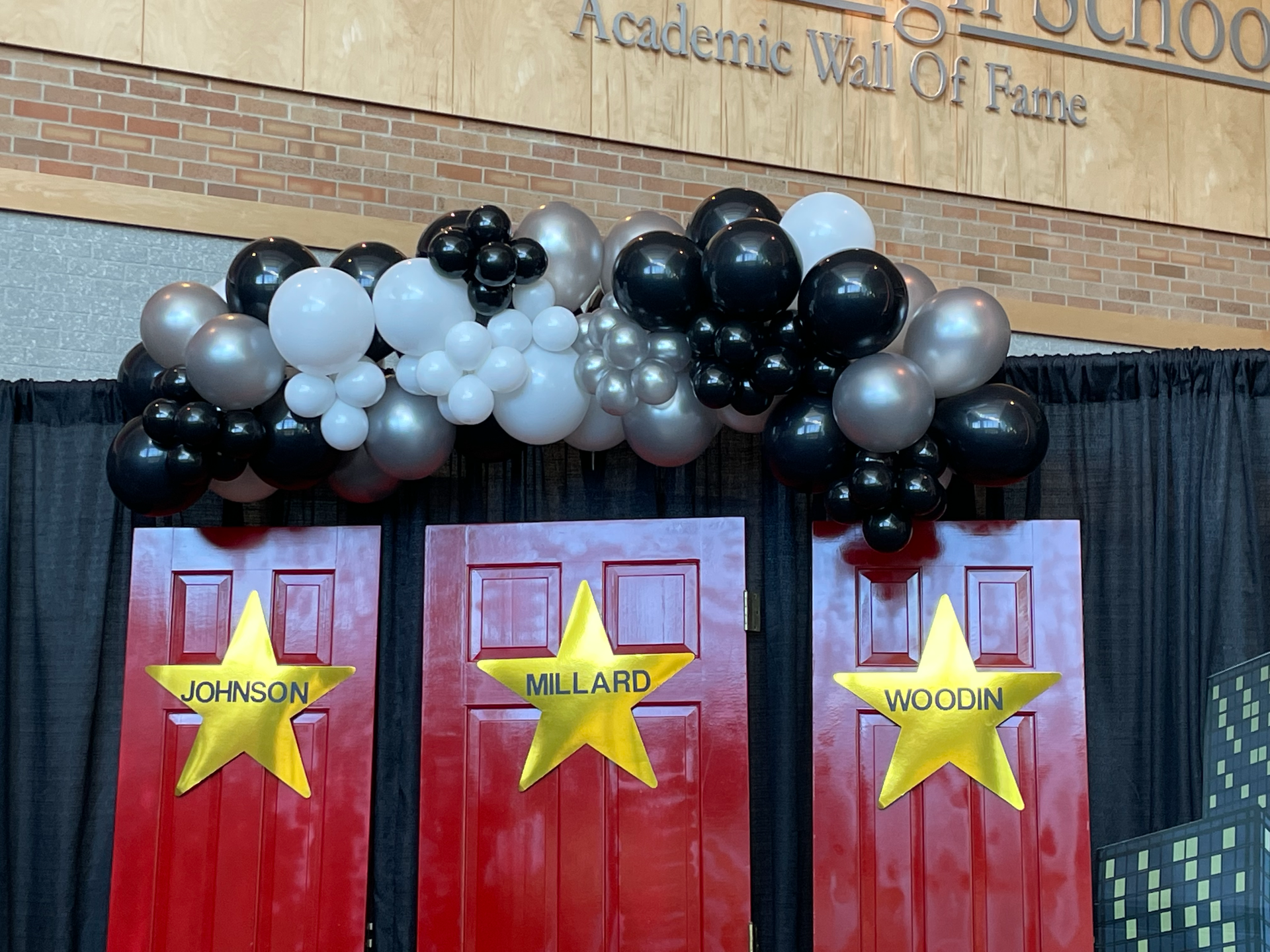 Three red doors are decorated with balloons and stars.