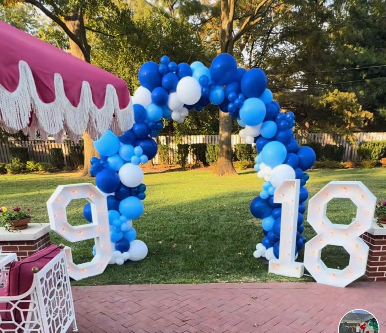 A blue and white balloon arch with the number 18 in front of it