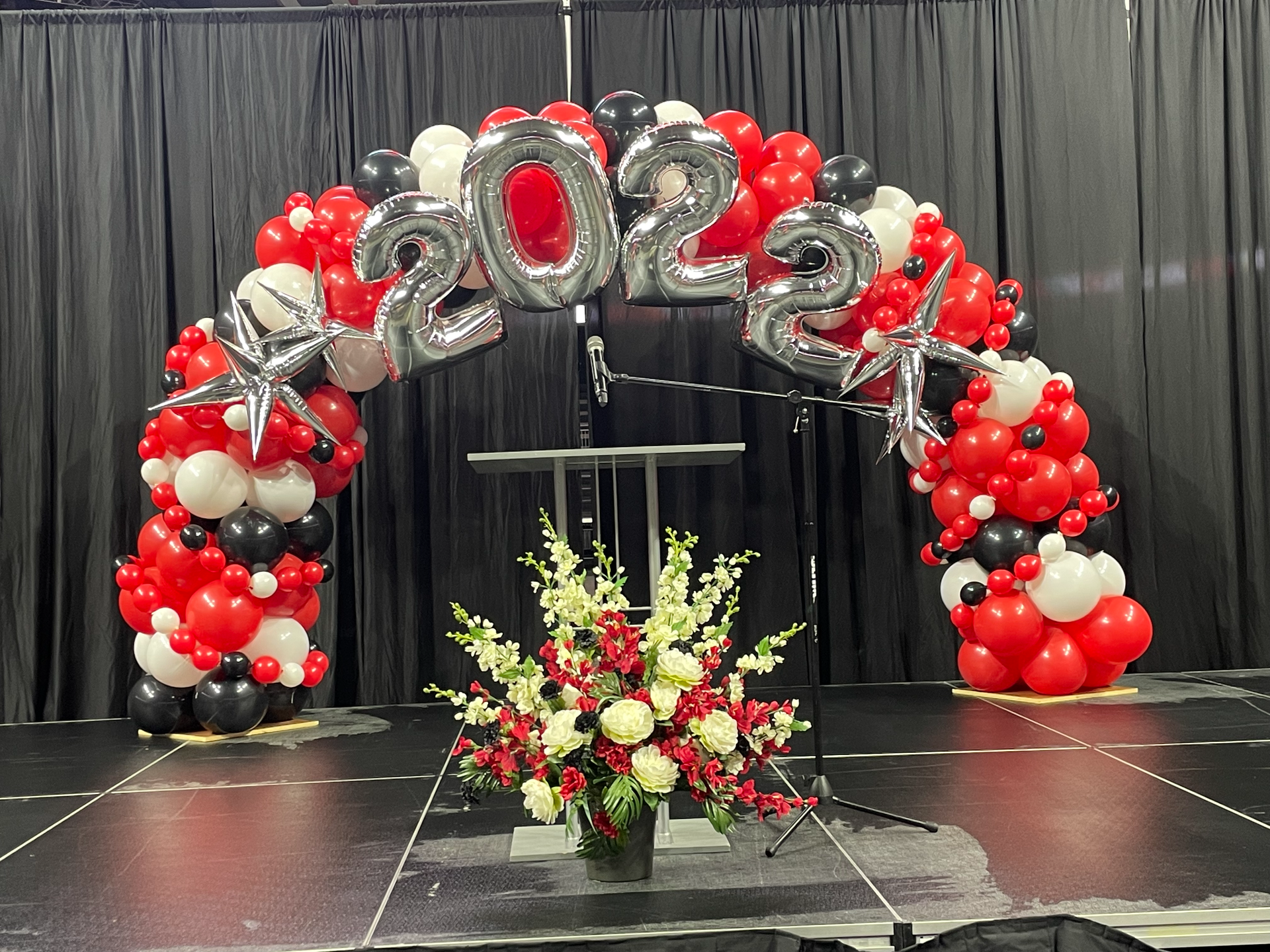 A stage decorated with balloons and flowers for a graduation ceremony.