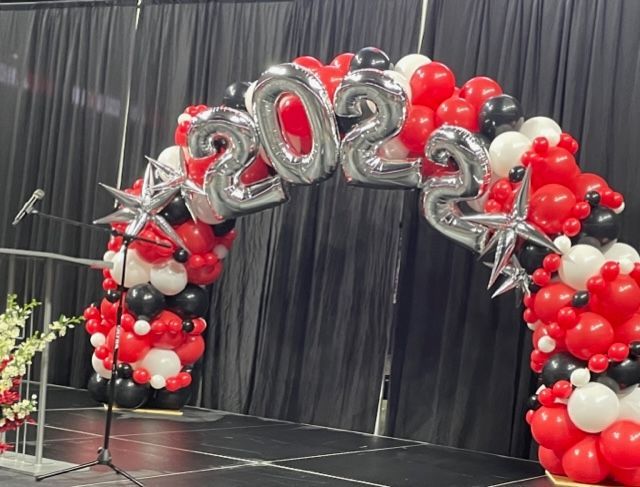 A stage decorated with red , black and white balloons and a microphone.