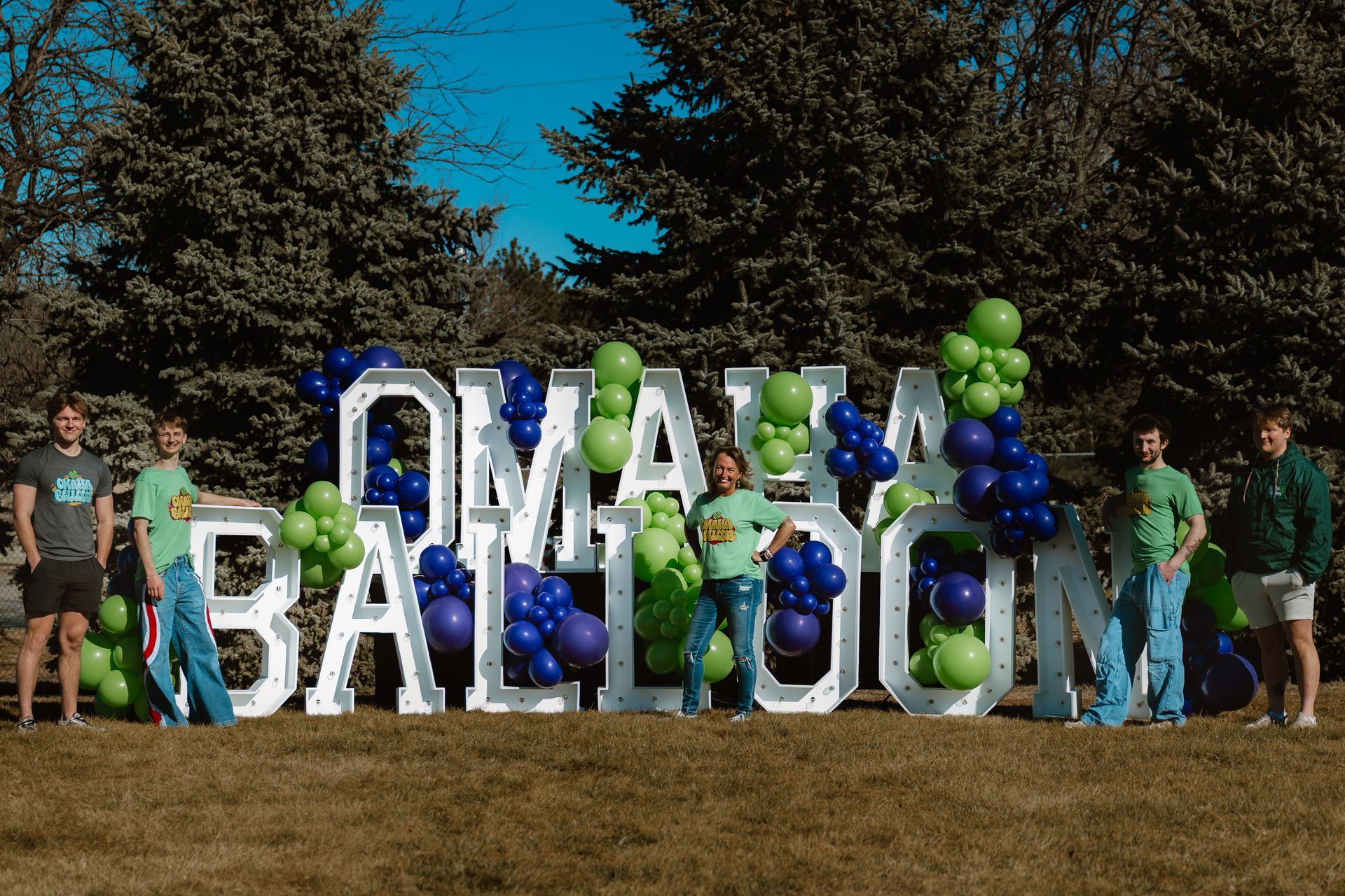 A group of people standing in front of a sign that says omaha balloons.