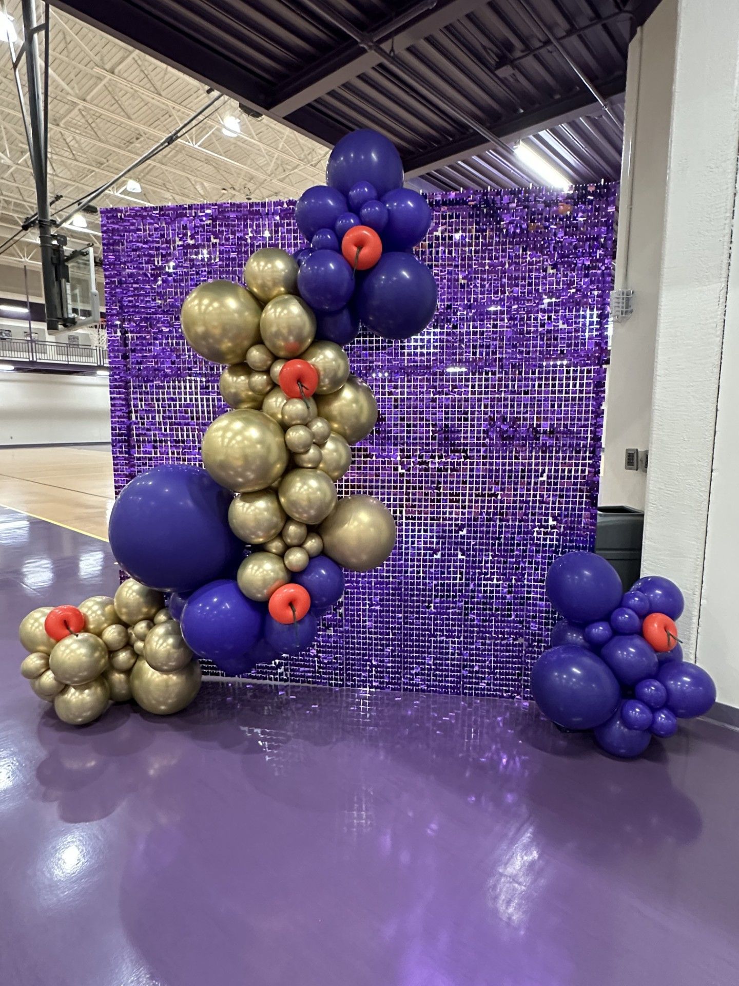 A bunch of balloons are sitting in front of a purple wall.