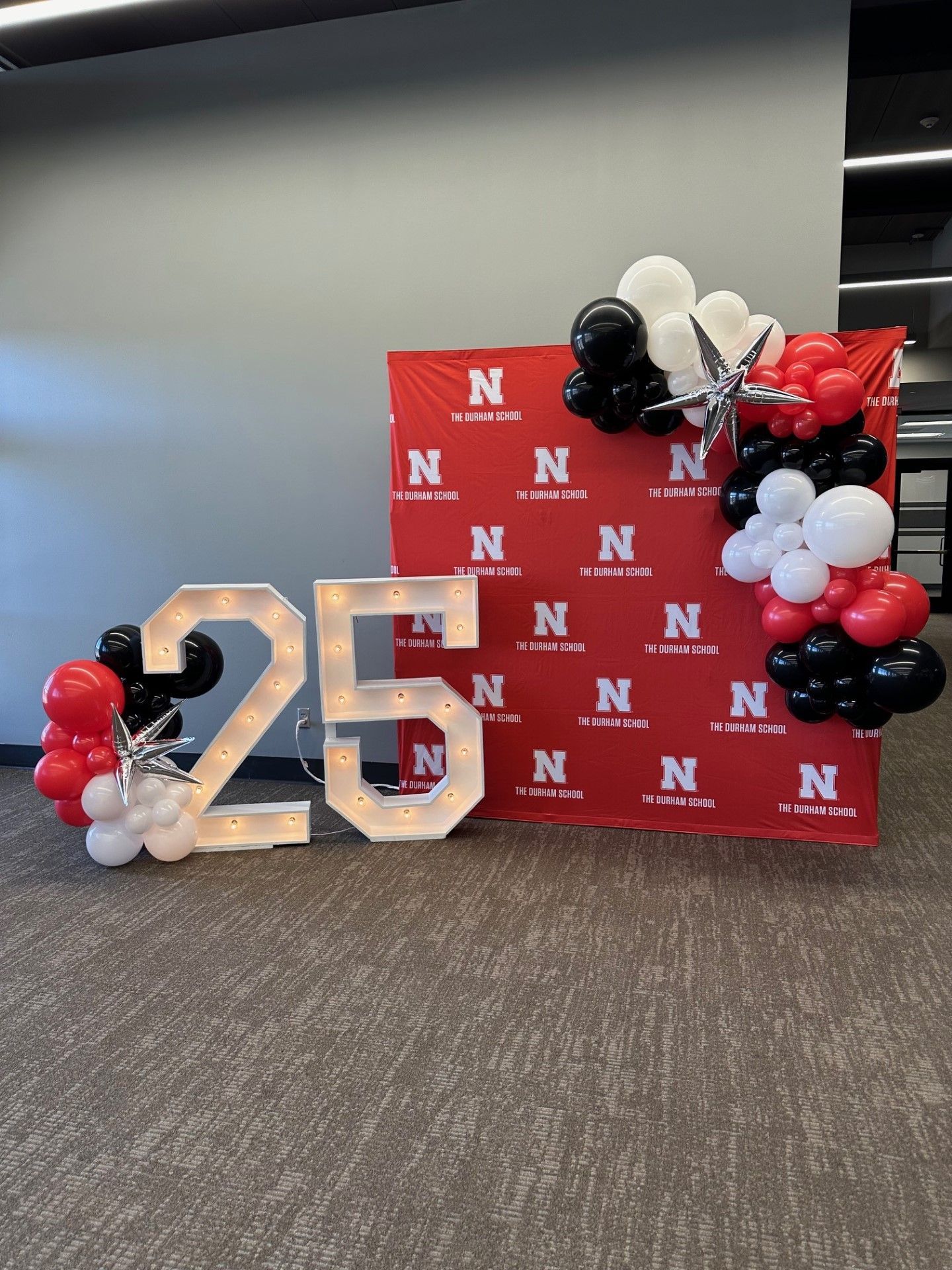 A large number 25 is surrounded by red , black and white balloons.