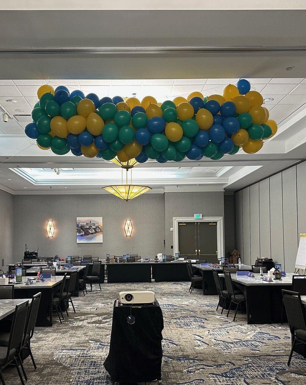 A large room with tables and chairs and balloons hanging from the ceiling.