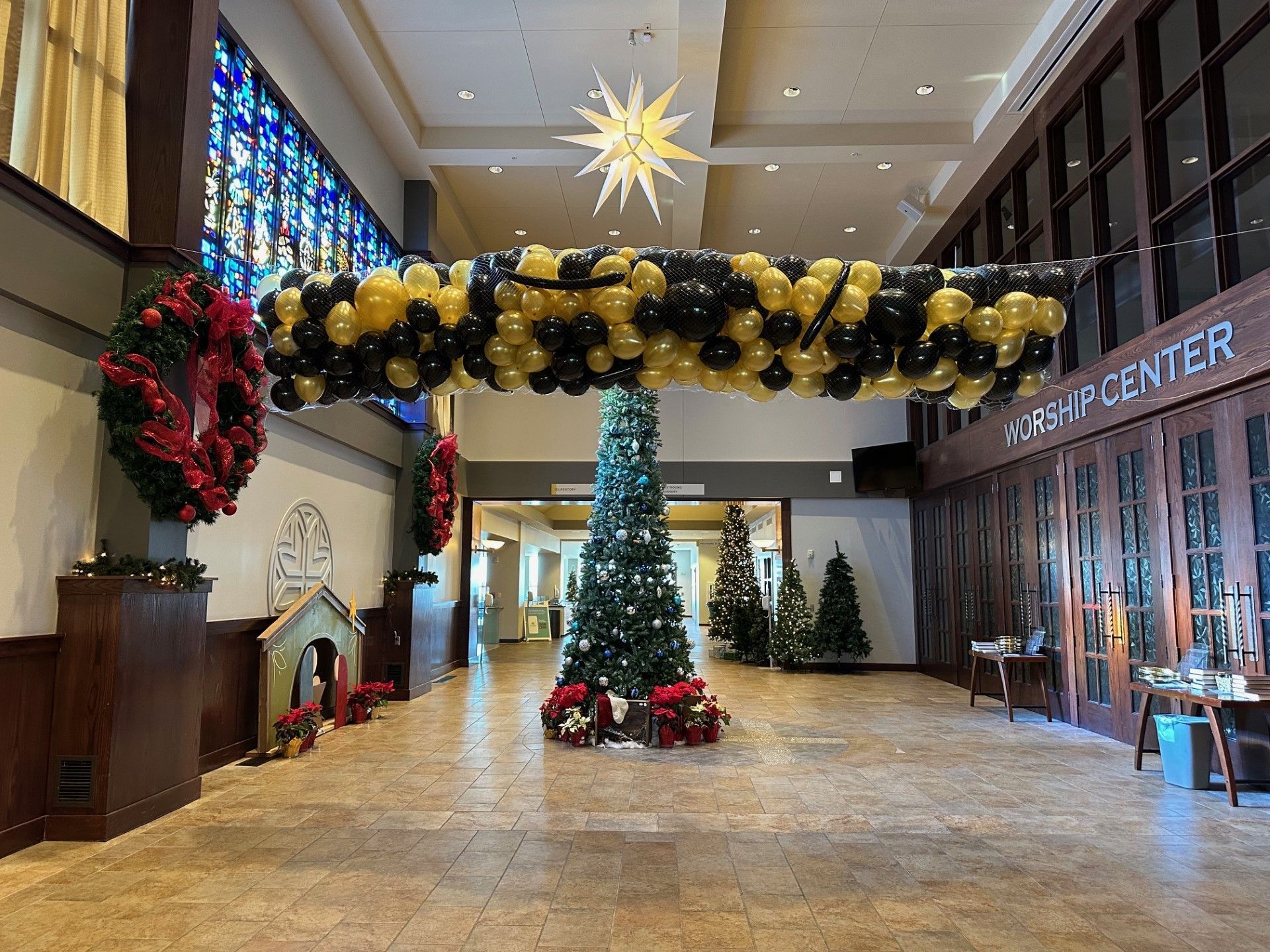 A church lobby decorated for christmas with balloons and a christmas tree.