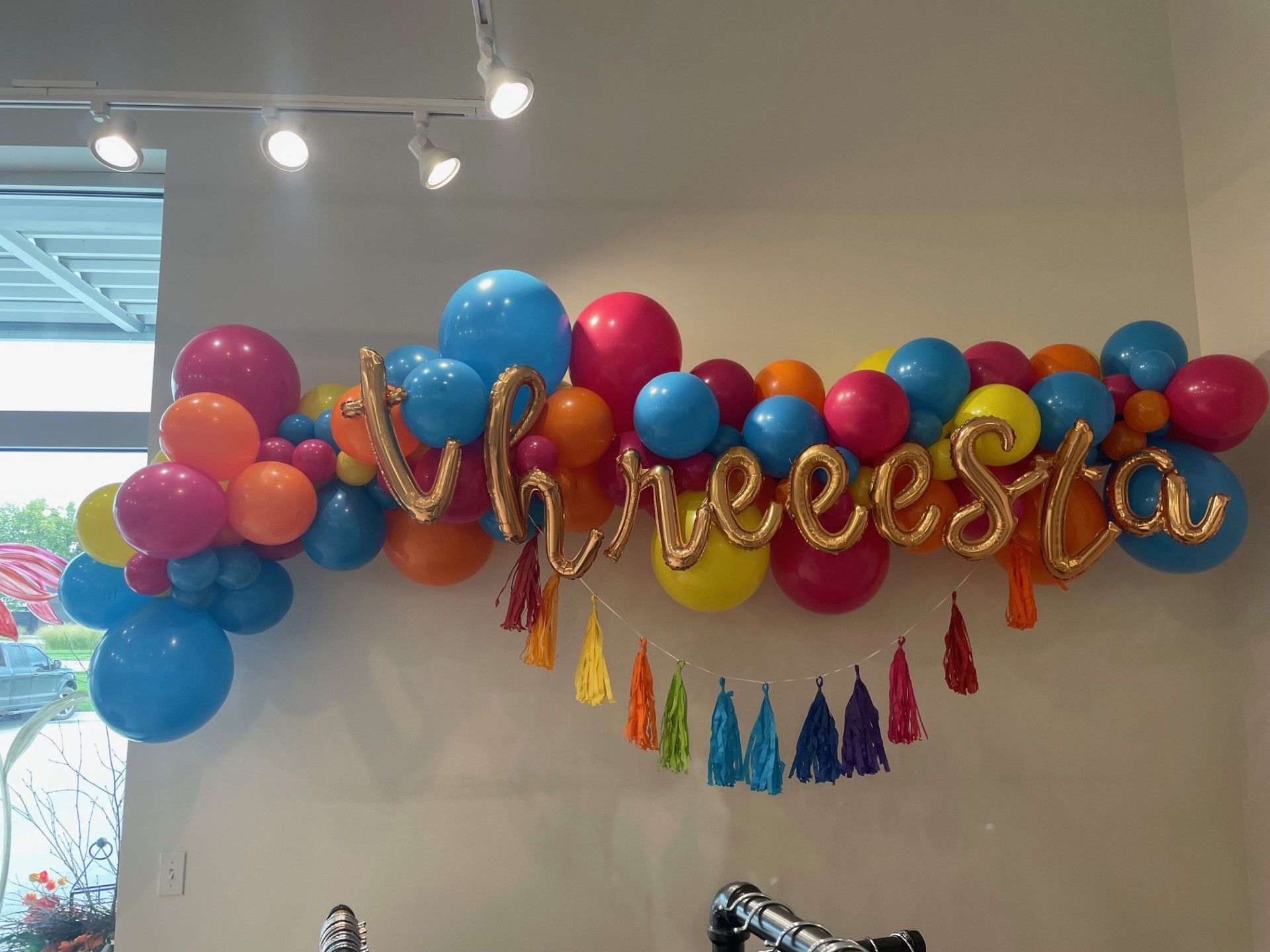 A bunch of colorful balloons are hanging on a wall.