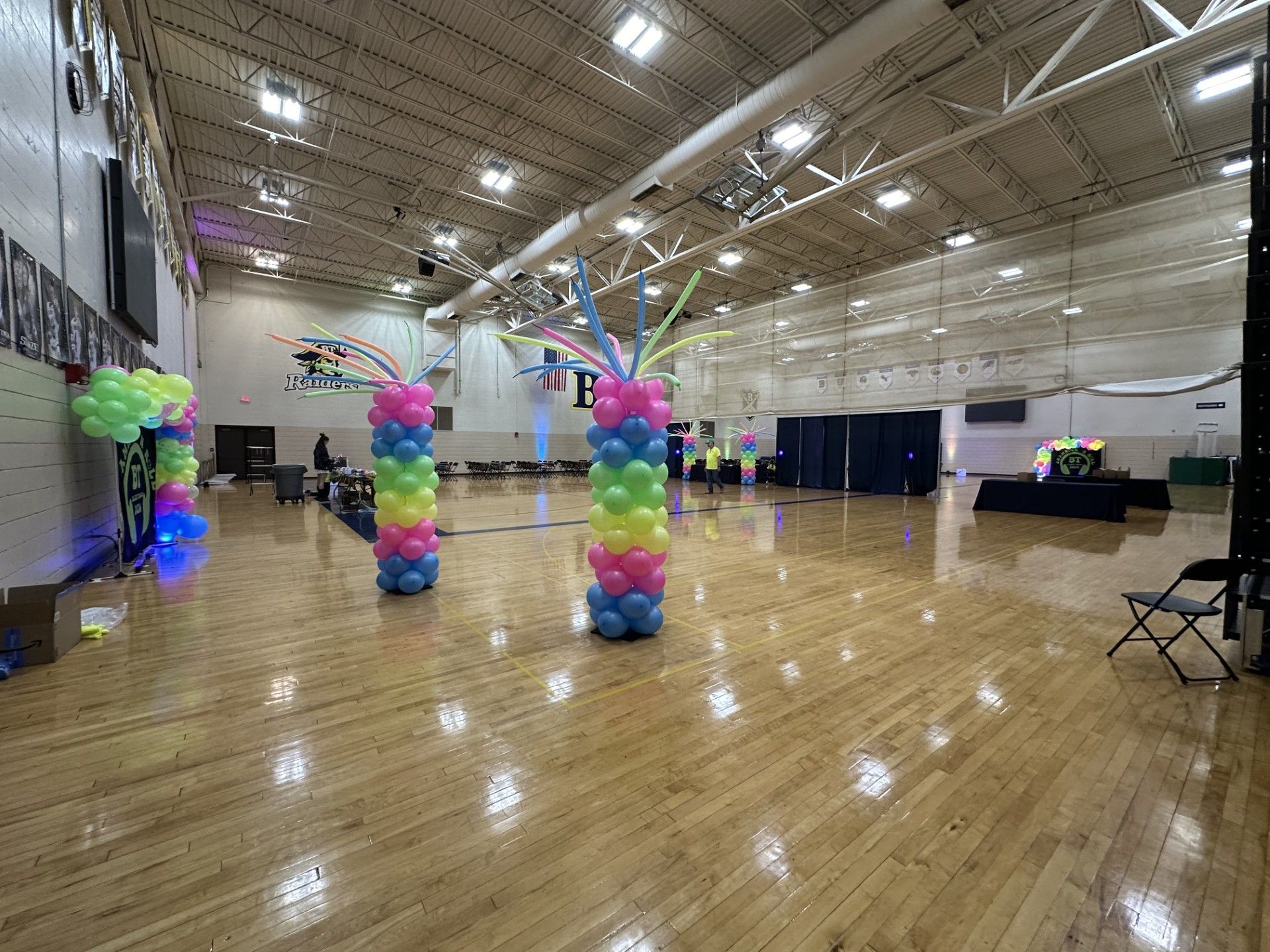 A large empty gym filled with balloons and chairs.