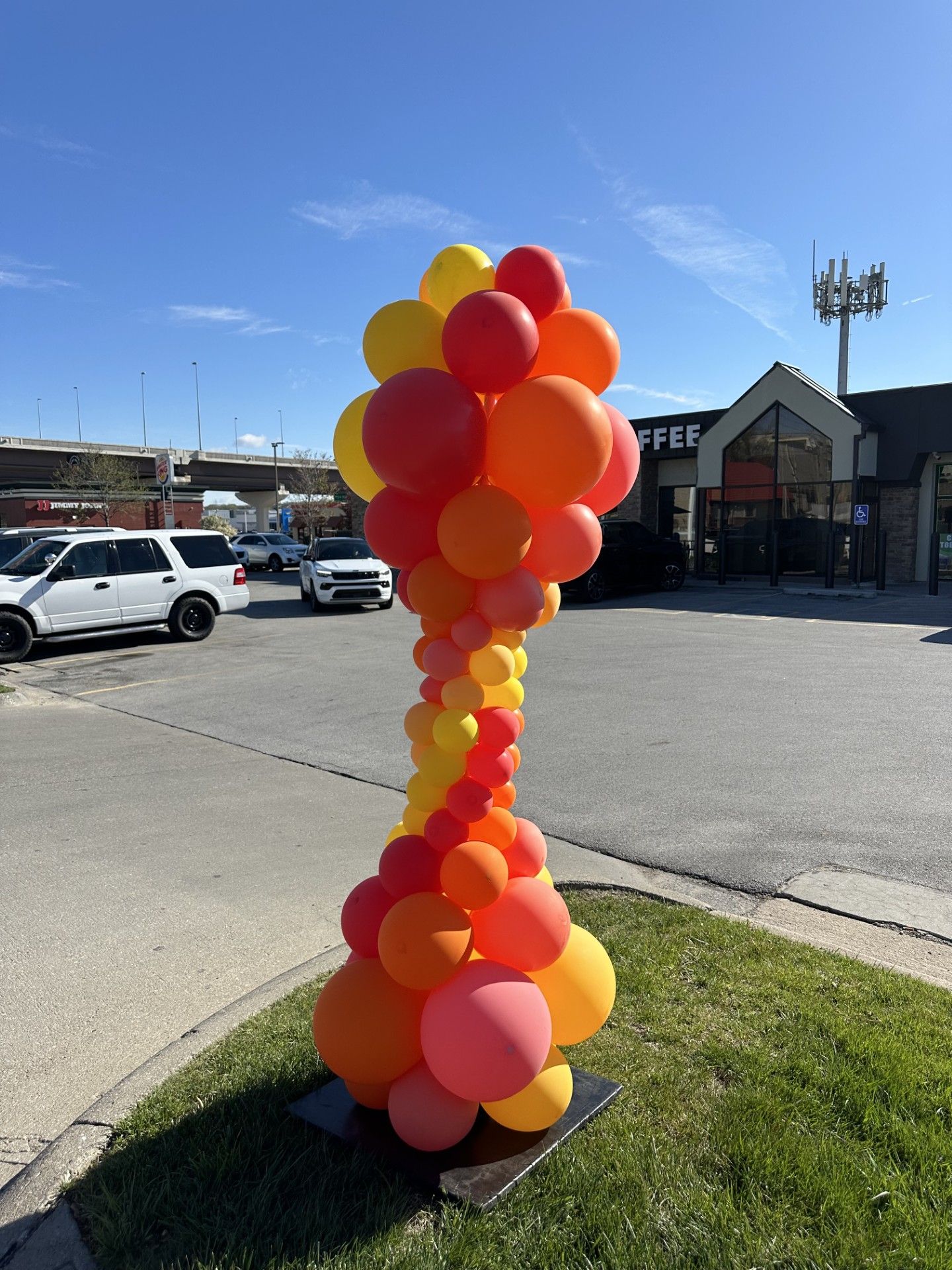 A bunch of balloons are stacked on top of each other in a parking lot.