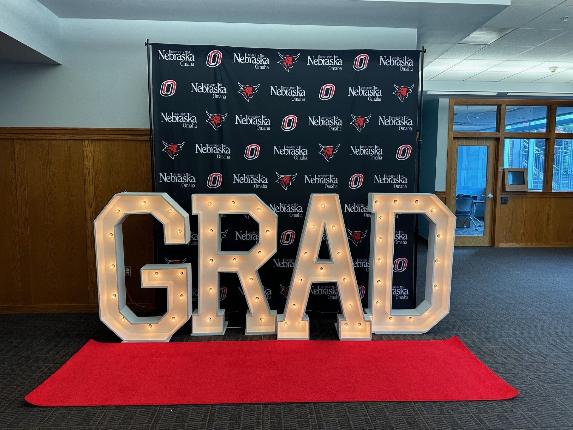 The word grad is lit up on a red carpet
