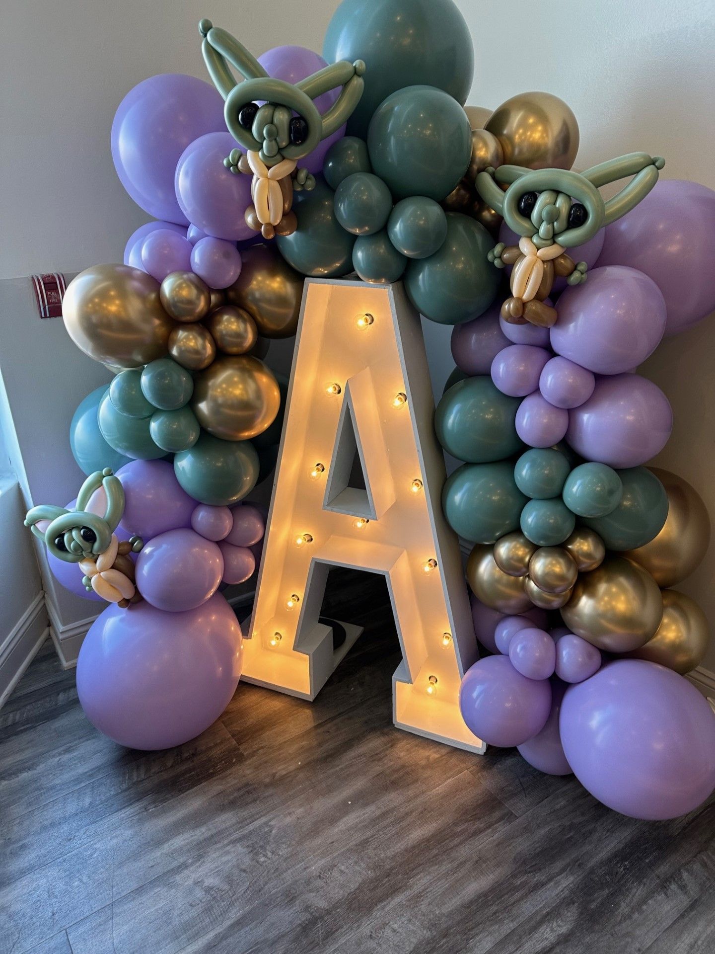 A large letter a is surrounded by balloons and lights.