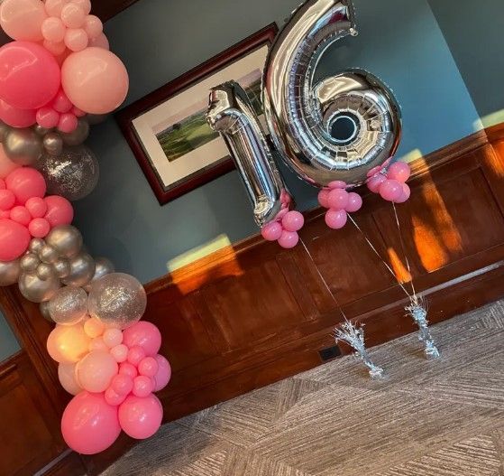 A bunch of pink and silver balloons with the number 16 on them