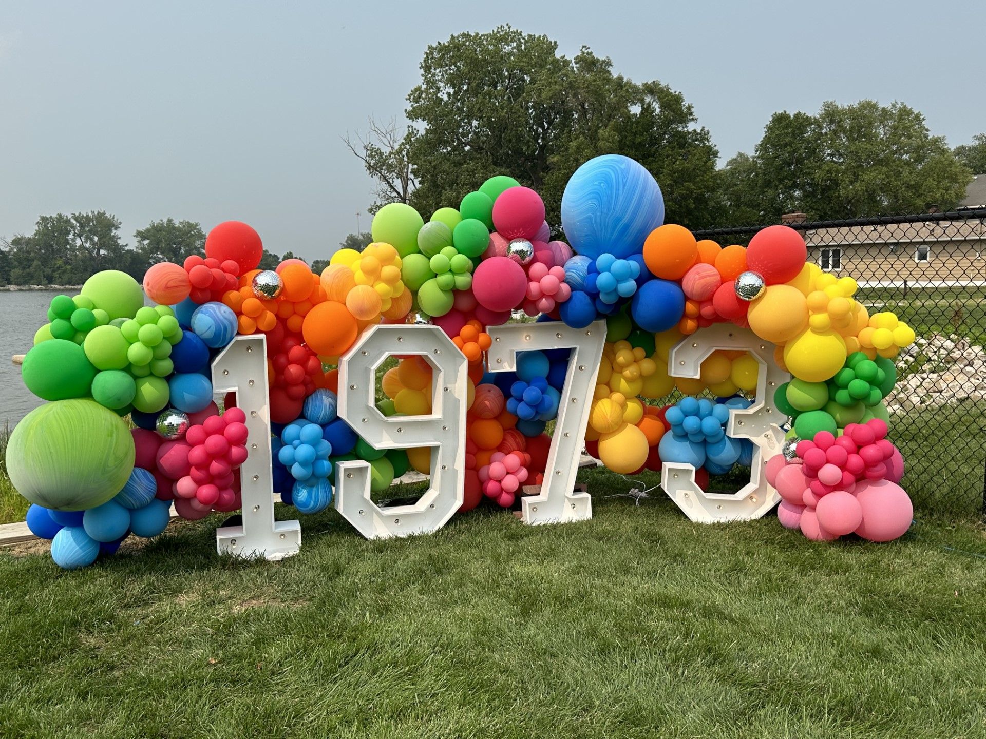 A bunch of colorful balloons are sitting on top of a lush green field.