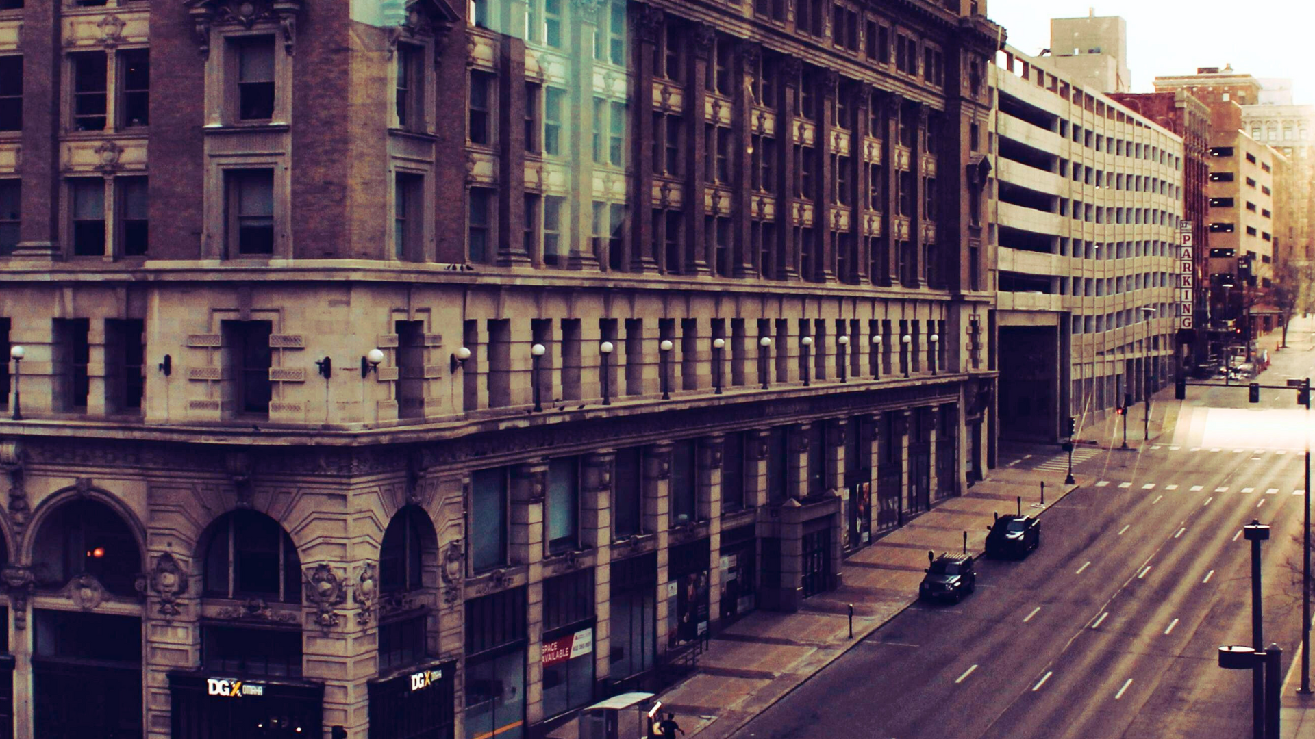 An aerial view of a city street with a large building in the background