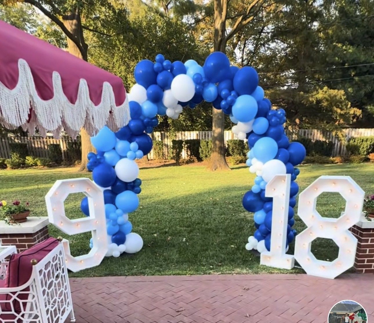 A blue and white balloon arch with the number 18 in front of it