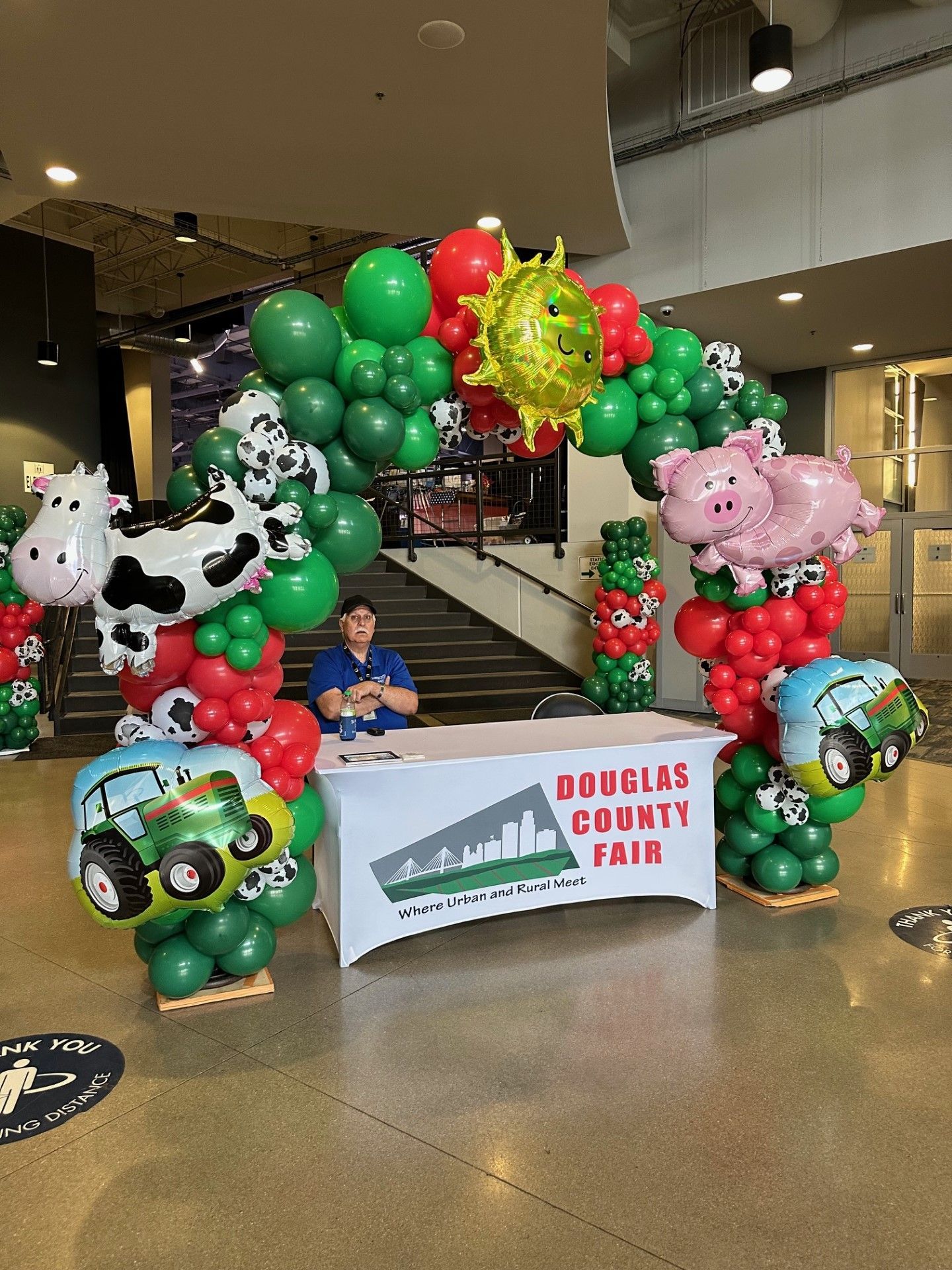 A man is sitting at a table surrounded by balloons.