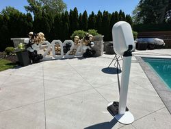 A photo booth is sitting on a patio next to a pool.