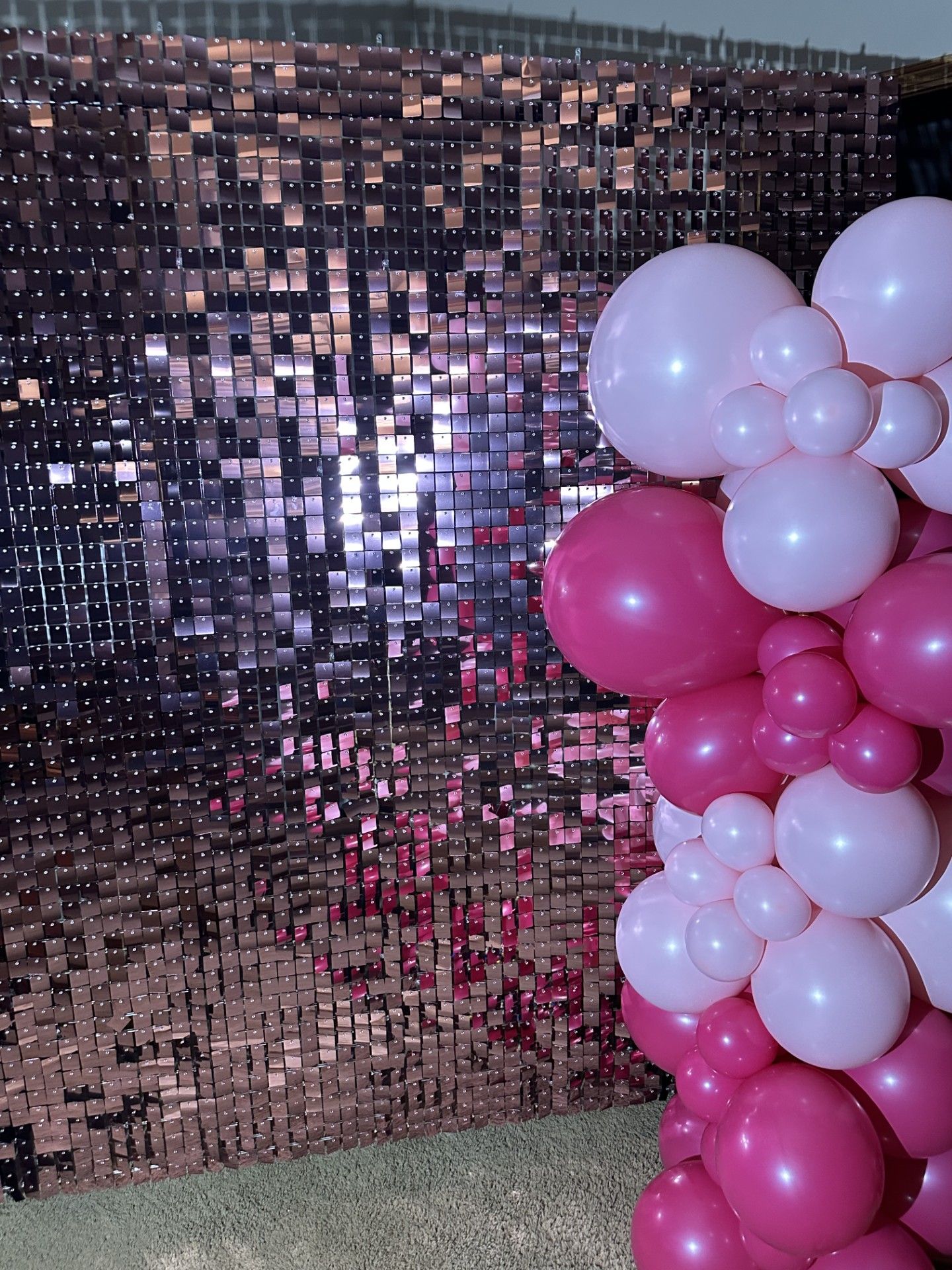 A bunch of pink balloons are sitting in front of a wall.