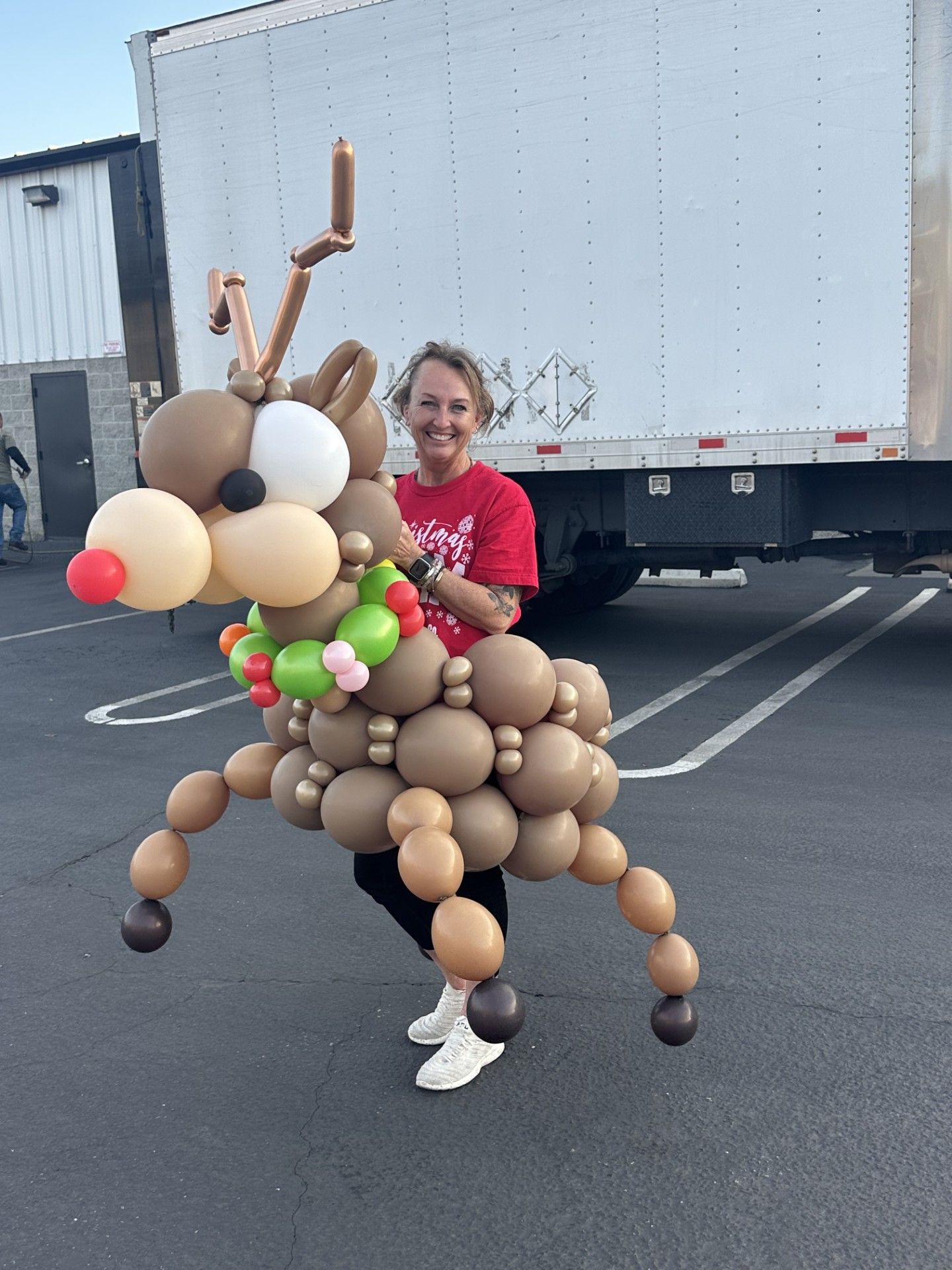 A woman is holding a reindeer made out of balloons.