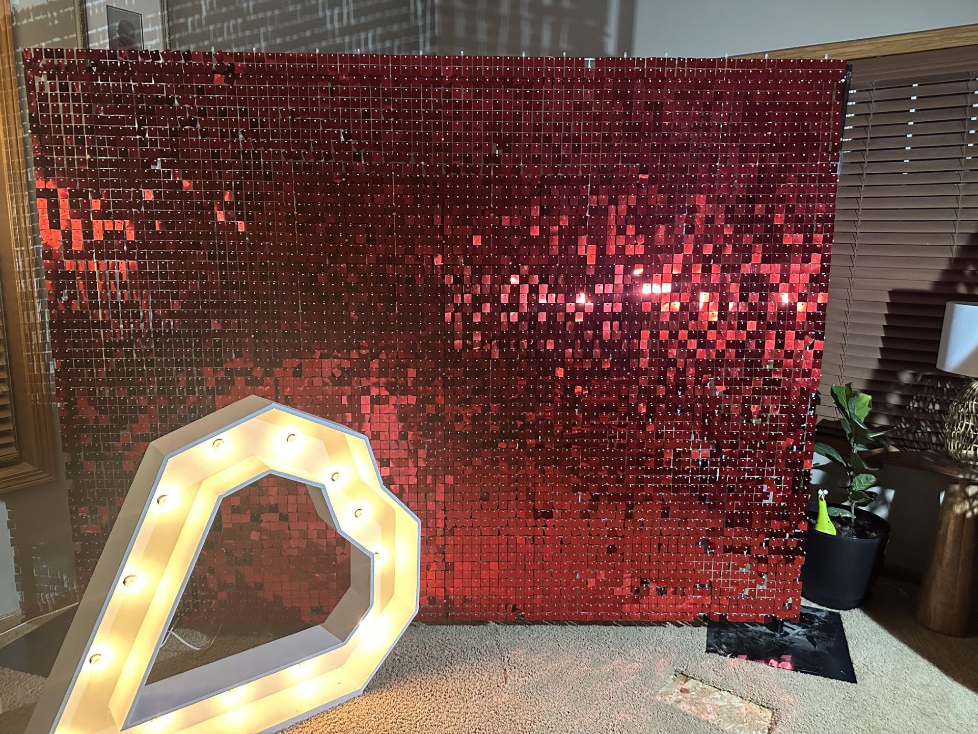 A bunch of pink and white balloons are sitting on the floor in front of a red wall.