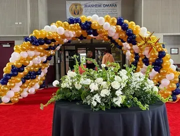A table with a balloon arch and flowers on it.