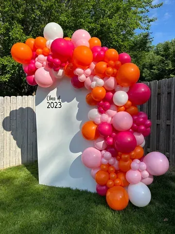 A bunch of balloons are sitting on top of a white wall.