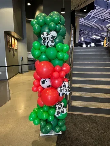 A bunch of balloons are stacked on top of each other in a room next to stairs.
