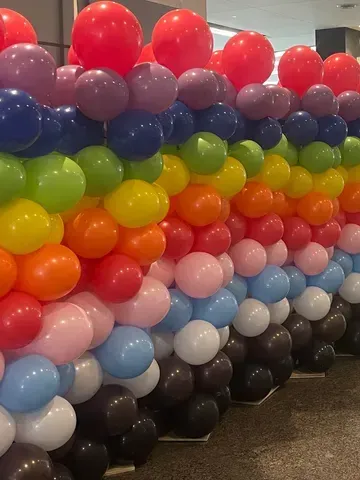 A wall of colorful balloons in the shape of a rainbow
