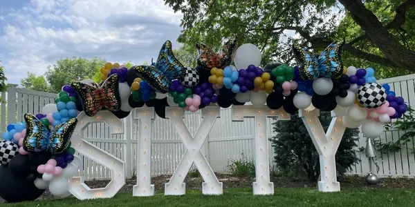 A sign that says sixty is surrounded by balloons.