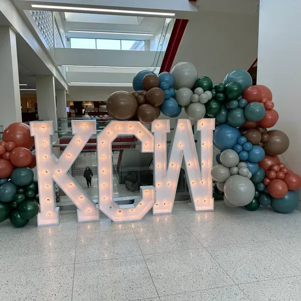 The word kcw is surrounded by balloons and lights