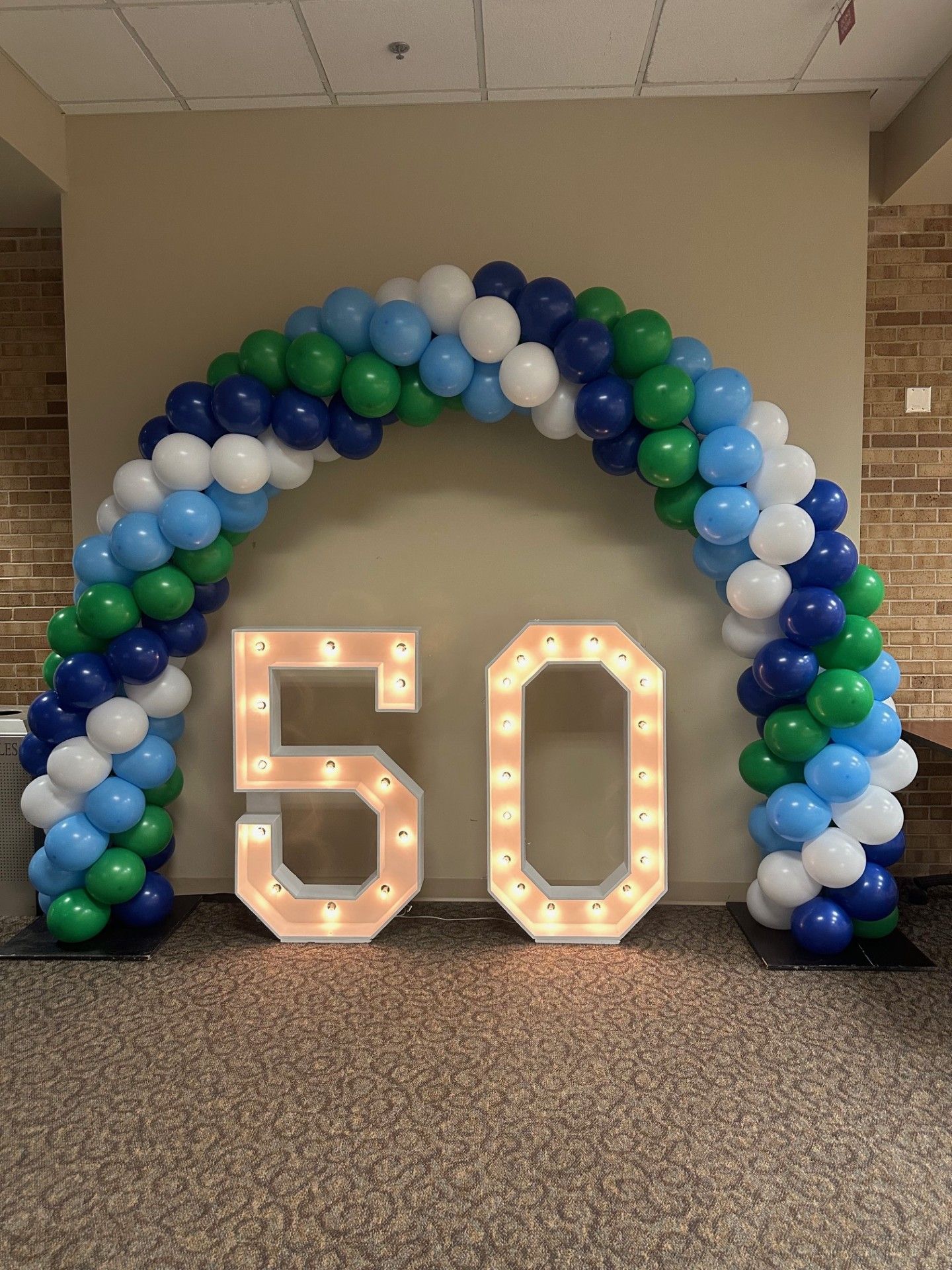 A rainbow colored balloon arch is in a gym.