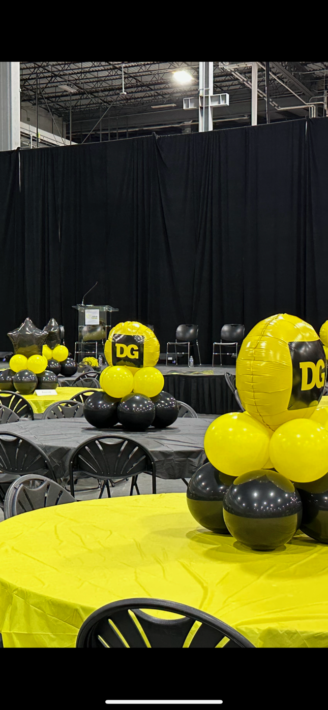 A room filled with tables and chairs decorated with yellow and black balloons.