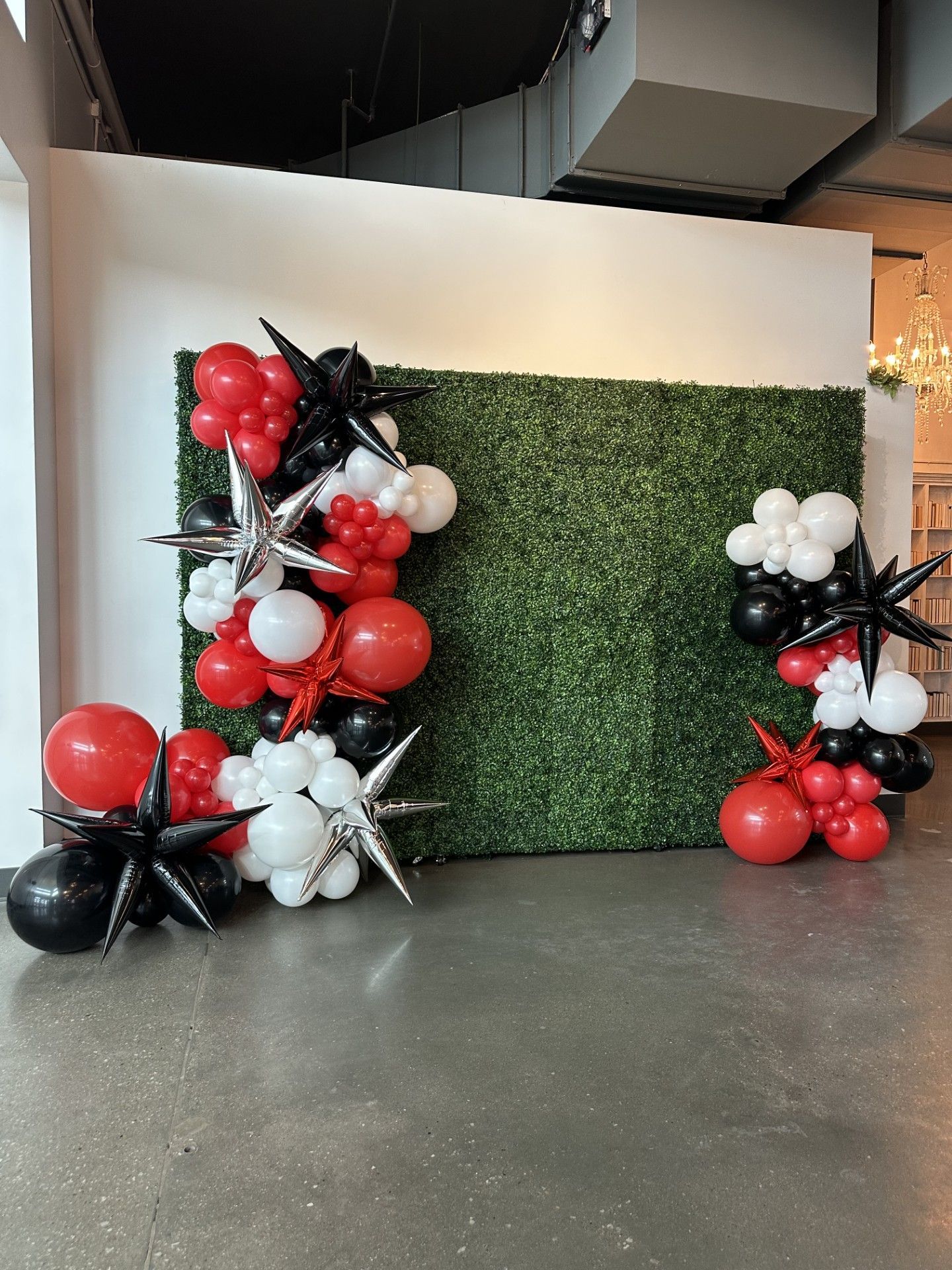 A bunch of red , white and black balloons are sitting in front of a green wall.