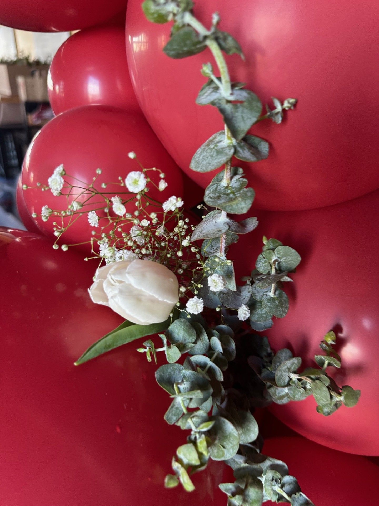 A gravestone with purple , green , and silver balloons on it.