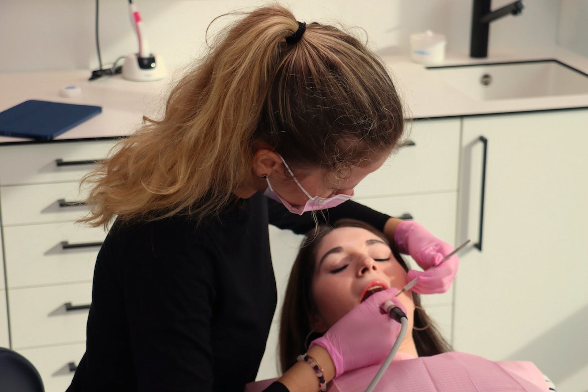 Ein Zahnarzt untersucht in seiner Zahnarztpraxis die Zähne eines Patienten mit Instrumenten.