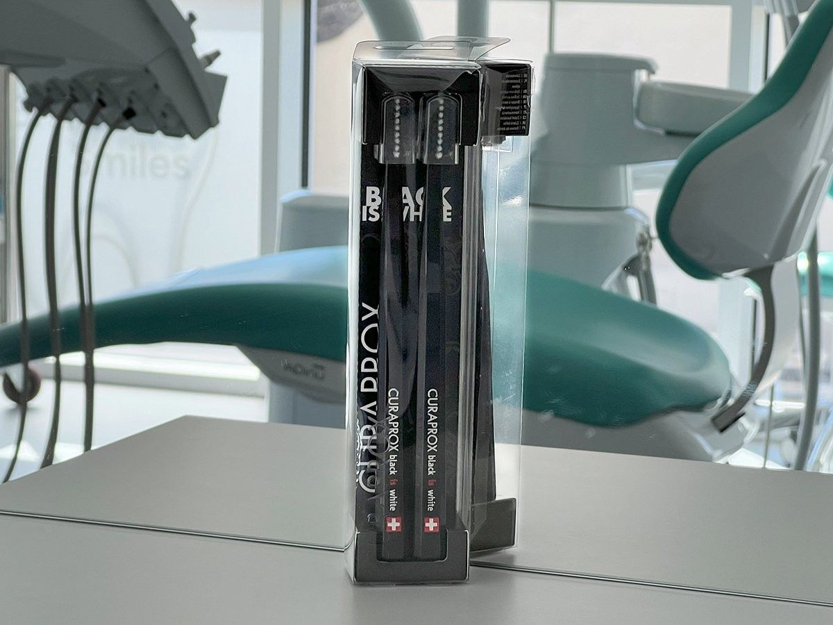 Zahnhygiene-Instrumente in einer durchsichtigen Kunststoffverpackung, im Hintergrund ein Zahnarztstuhl.