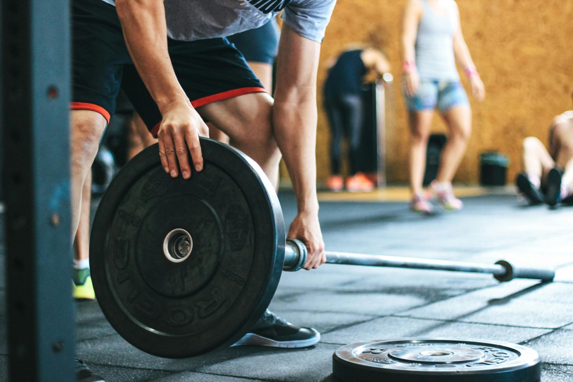 A man is lifting a barbell in a gym.