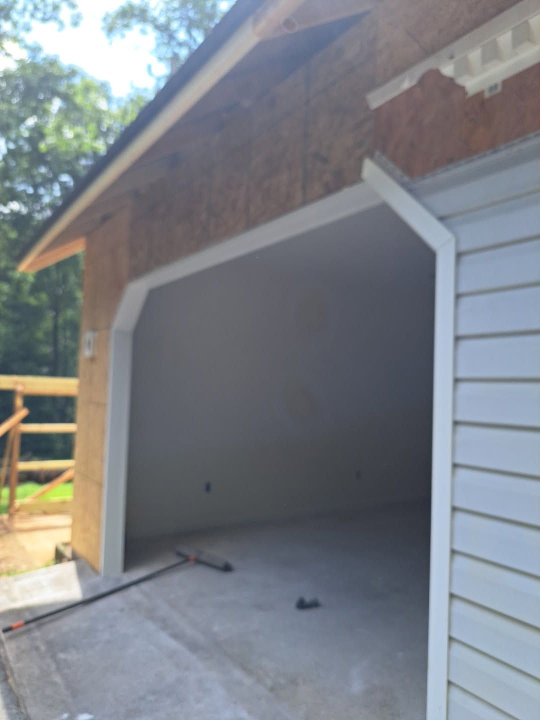 Open garage with white trim and gray floor in a brick-and-siding house exterior.