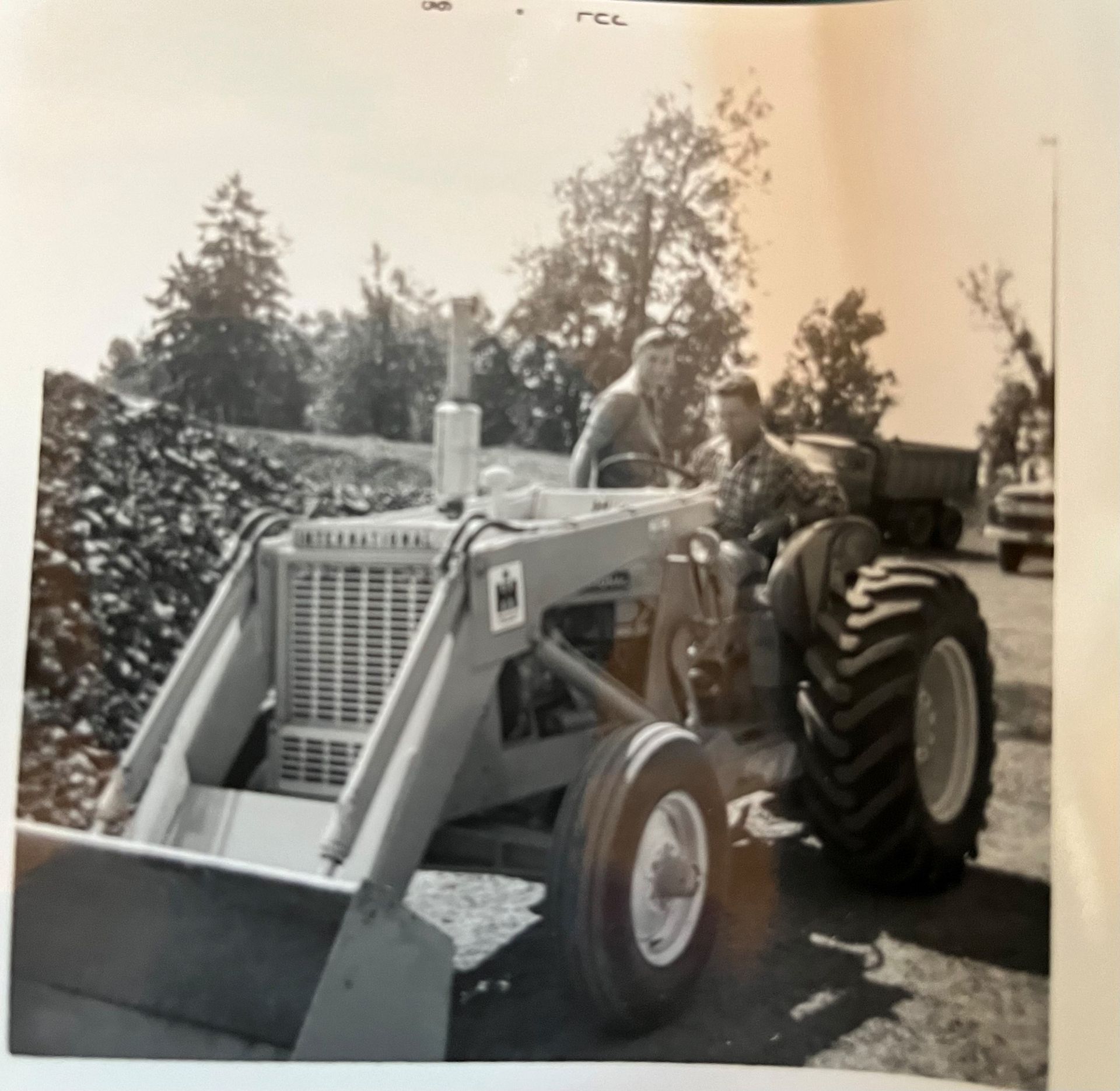 A black and white photo of a man driving a tractor