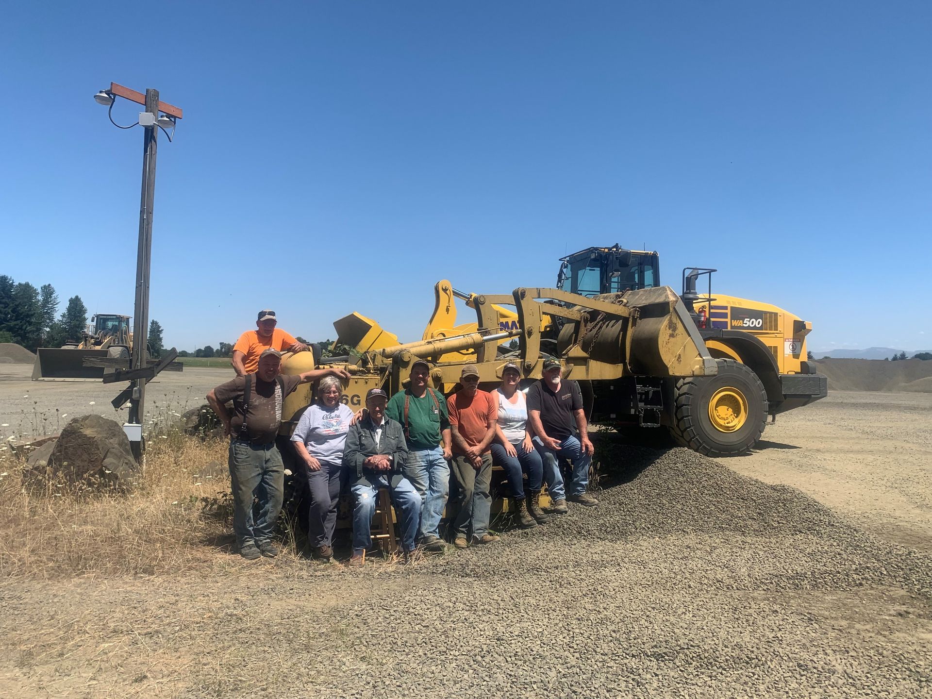 A group of people are posing for a picture in front of a bulldozer.