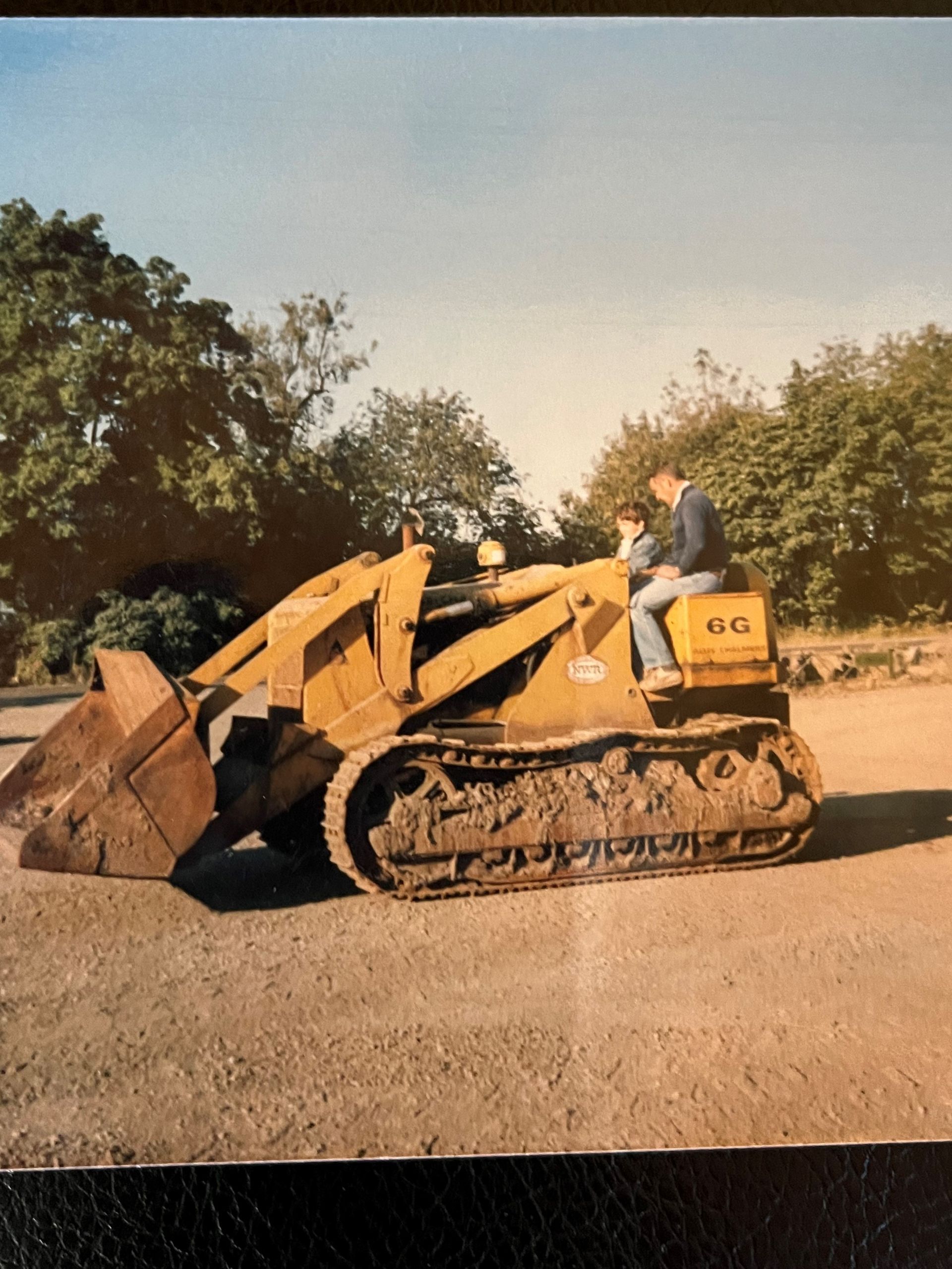 A man sits on a yellow tractor