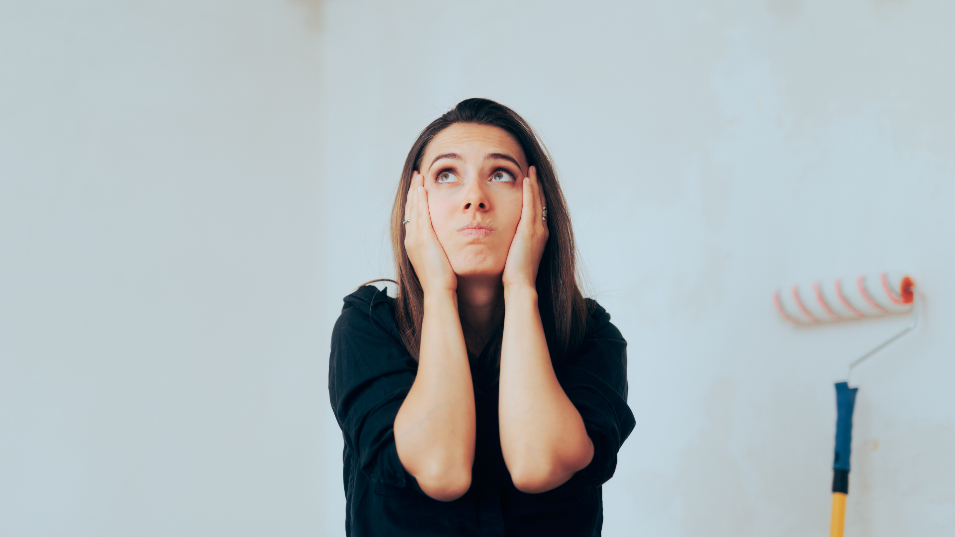 A woman is covering her ears with her hands while looking up.